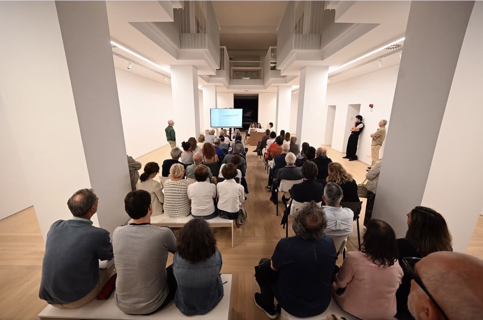 Público sentado en las salas del museo escuchando una presentación