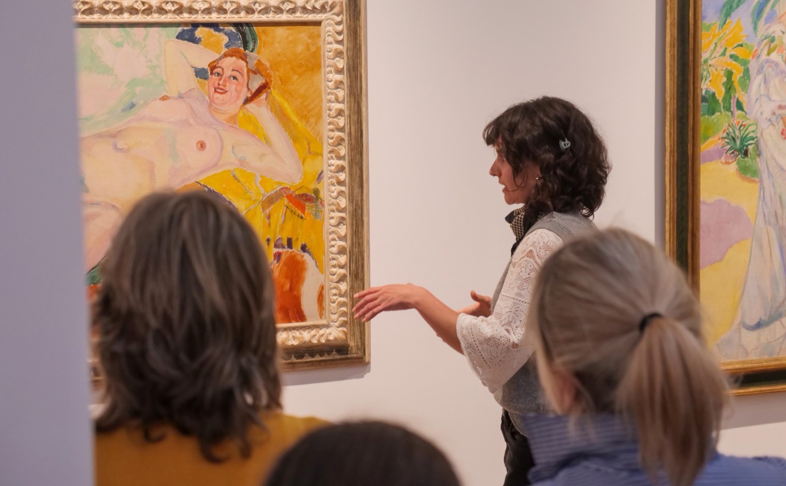 Una artista explica una pintura de la colección ante un grupo de visitantes