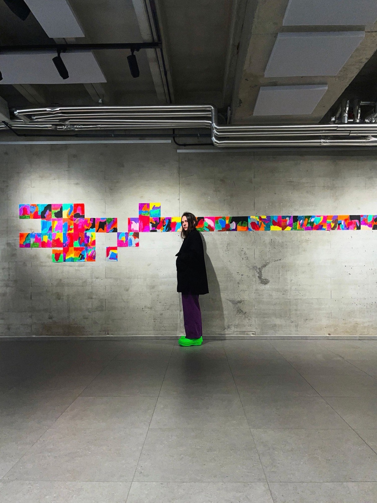 Mina K. junto a una instalación de dibujos de colores en una pared de hormigón