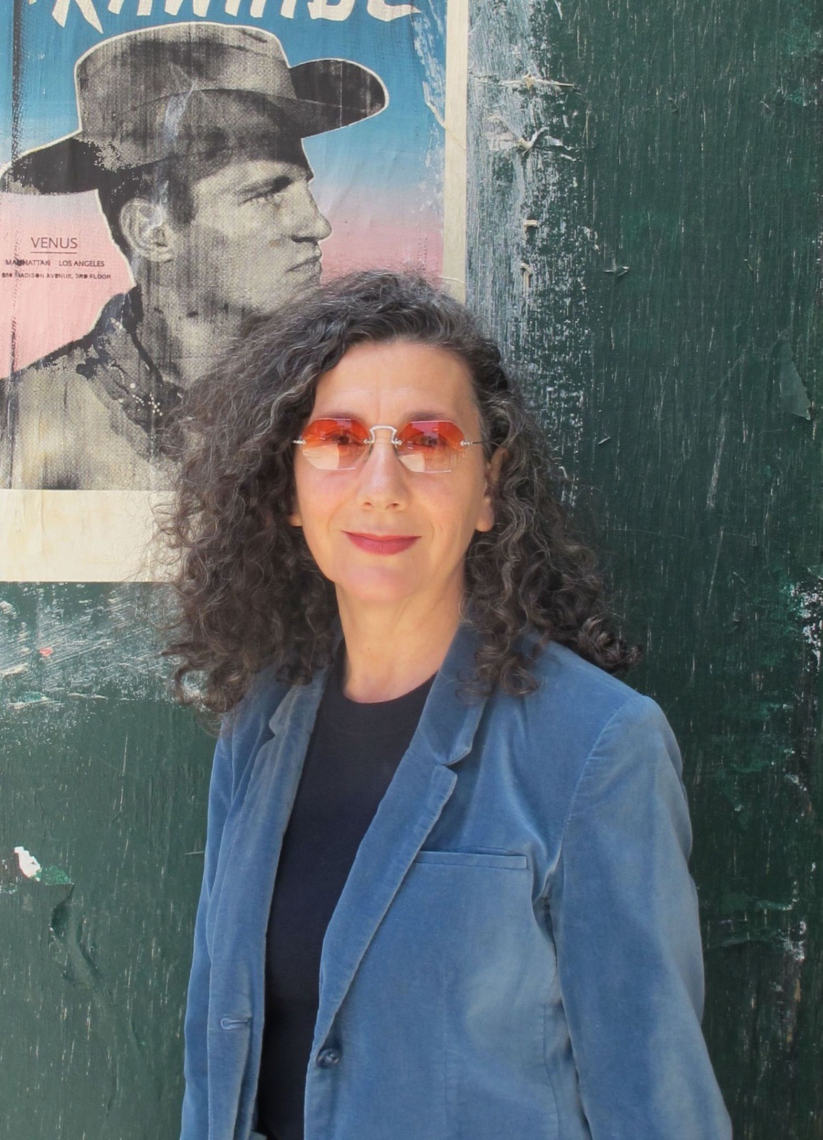 Retrato de Victoria Civera con gafas de sol ante un cartel antiguo